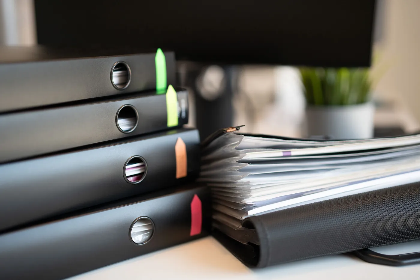 Stacked binders of paperwork on a desk